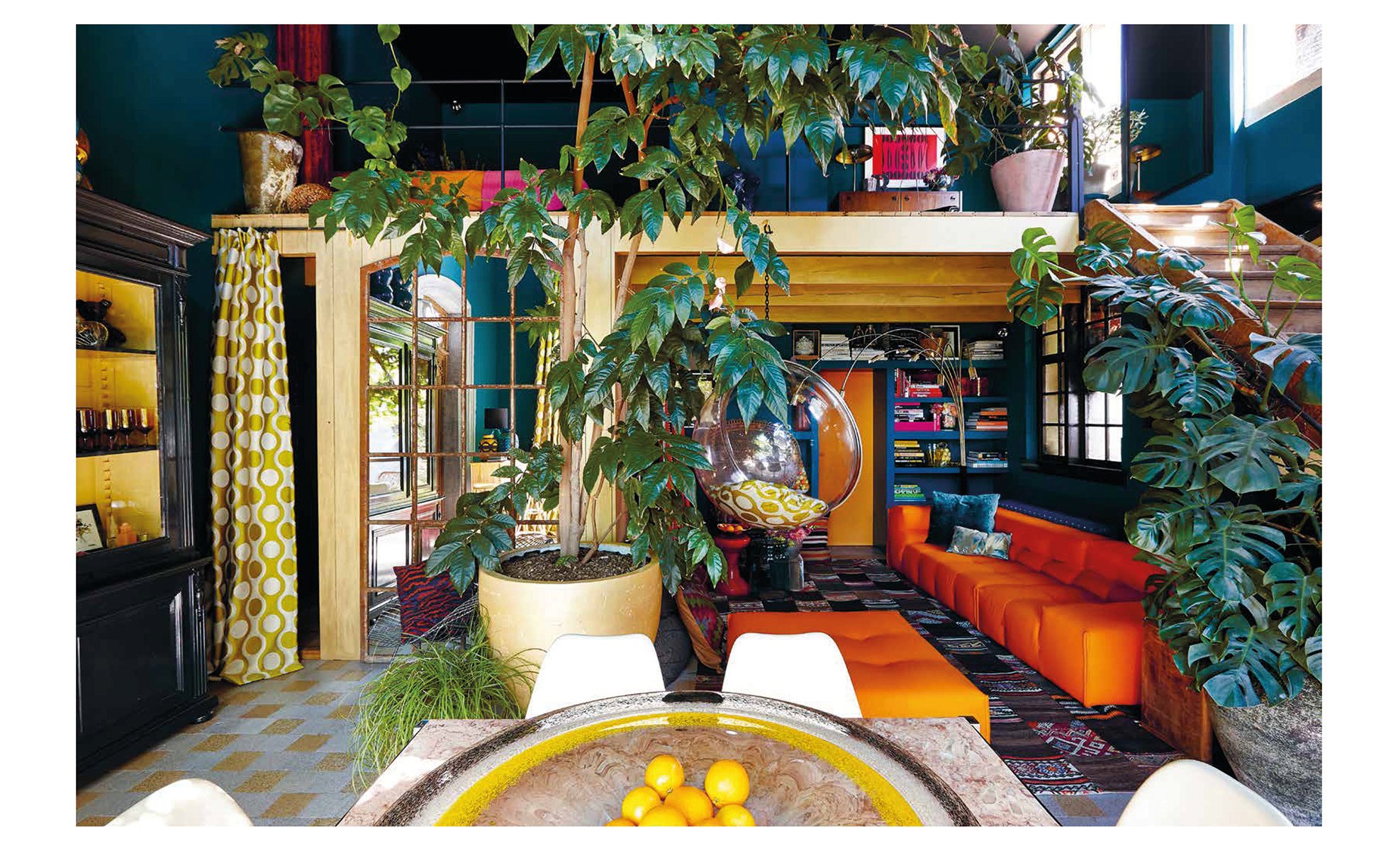 Aerial view of living space with tropical green foliage, palm leaves, 2 deckchairs, on pale pink cover of 'Ultimate Wonder Plants, Your Urban Jungle Interior', by Lannoo Publishers.