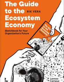 Hand passing book to another hand, on orange cover of 'The Guide to the Ecosystem Economy, Sketchbook for Your Organization’s Future', by Lannoo Publishers.