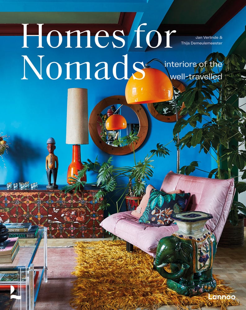 Exotic interior with bright blue wall with pink chair, yellow rug and 70s orange light fixture, on cover of 'Homes For Nomads, Interiors of the Well-Travelled', by Lannoo Publishers.