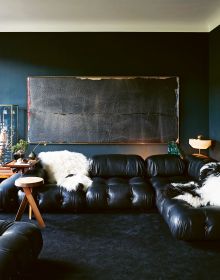 Exotic interior with bright blue wall with pink chair, yellow rug and 70s orange light fixture, on cover of 'Homes For Nomads, Interiors of the Well-Travelled', by Lannoo Publishers.