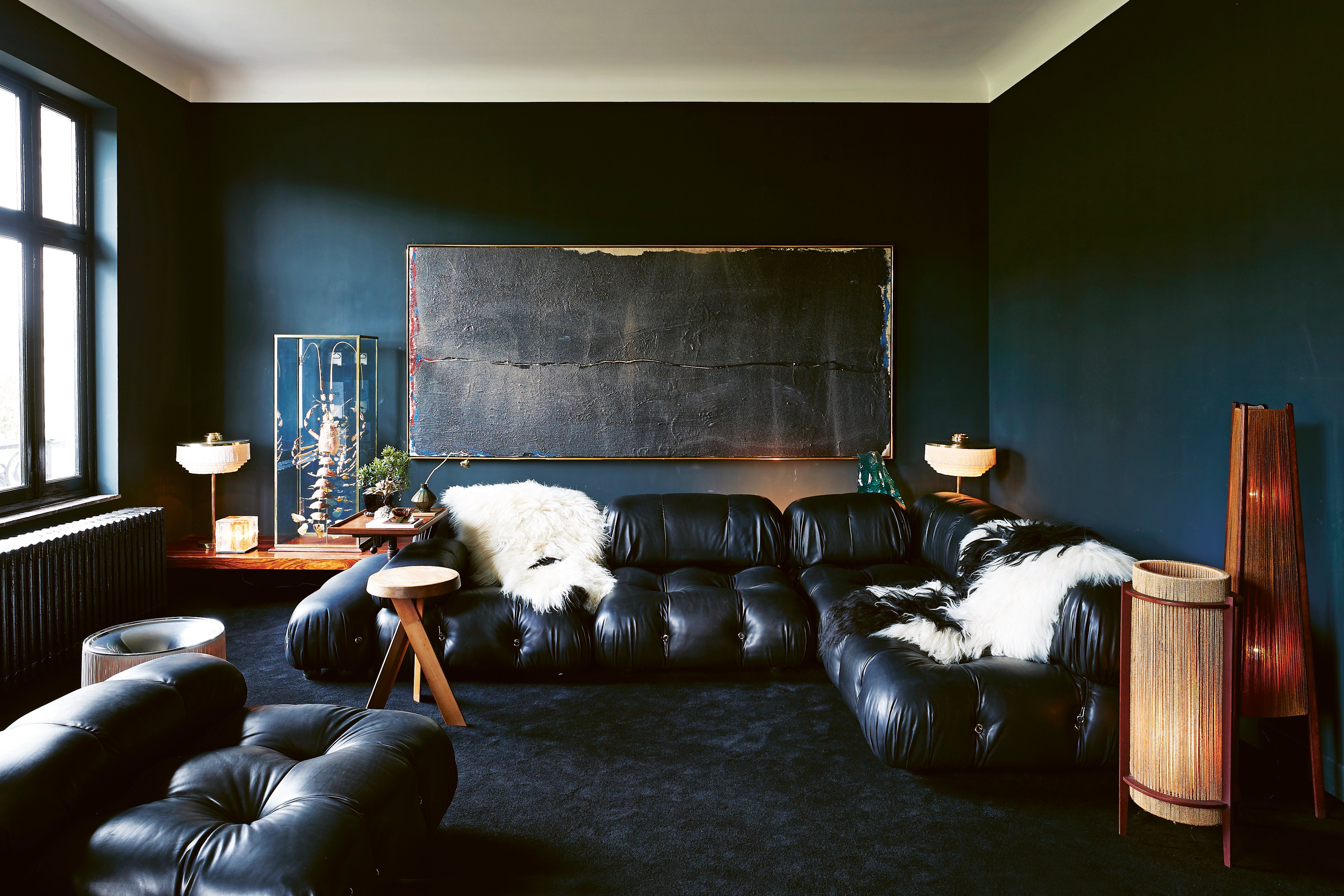 Exotic interior with bright blue wall with pink chair, yellow rug and 70s orange light fixture, on cover of 'Homes For Nomads, Interiors of the Well-Travelled', by Lannoo Publishers.