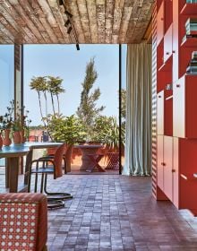 Exotic interior with bright blue wall with pink chair, yellow rug and 70s orange light fixture, on cover of 'Homes For Nomads, Interiors of the Well-Travelled', by Lannoo Publishers.