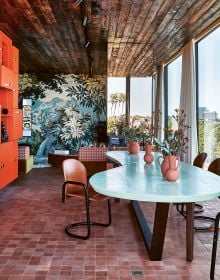 Exotic interior with bright blue wall with pink chair, yellow rug and 70s orange light fixture, on cover of 'Homes For Nomads, Interiors of the Well-Travelled', by Lannoo Publishers.