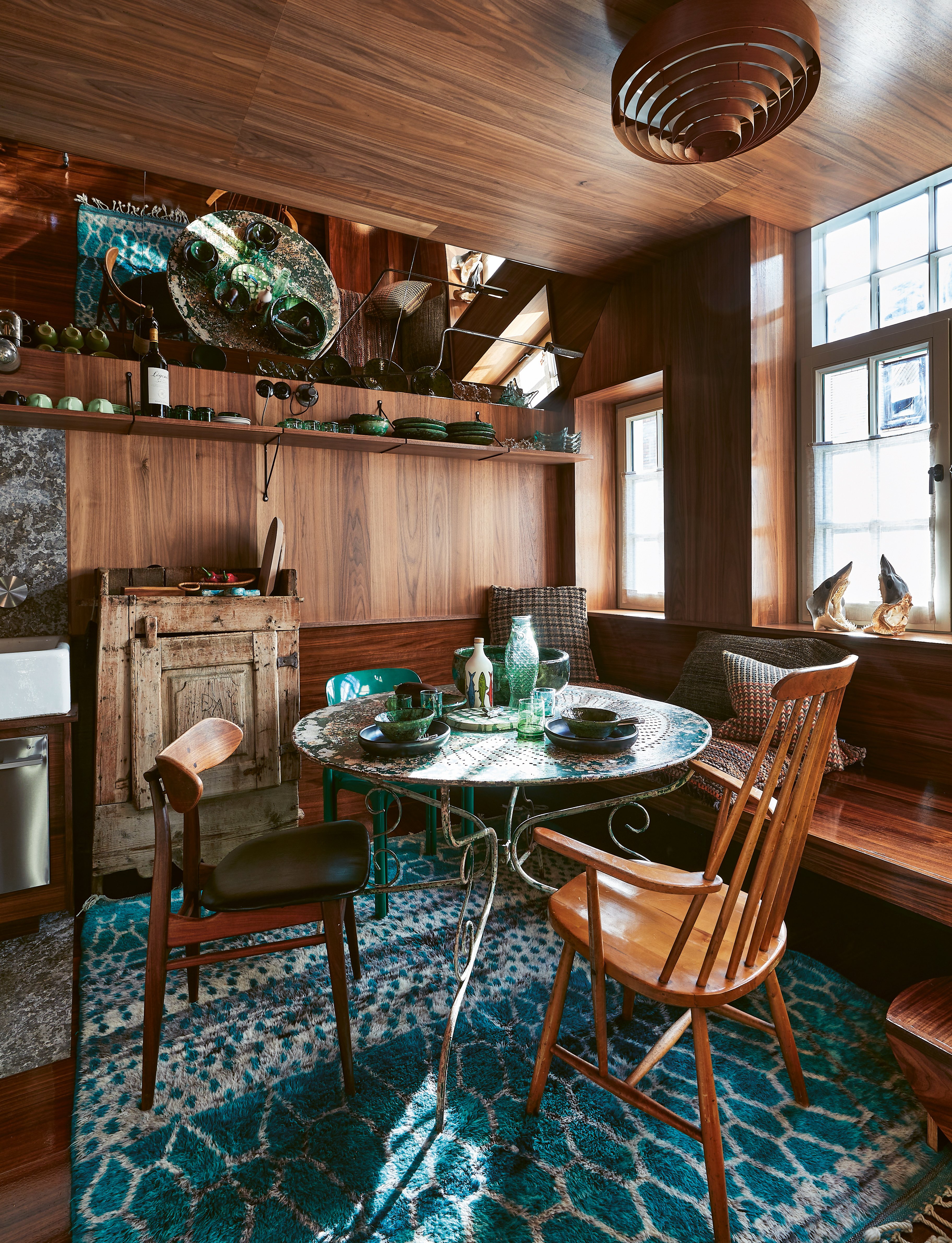 Exotic interior with bright blue wall with pink chair, yellow rug and 70s orange light fixture, on cover of 'Homes For Nomads, Interiors of the Well-Travelled', by Lannoo Publishers.