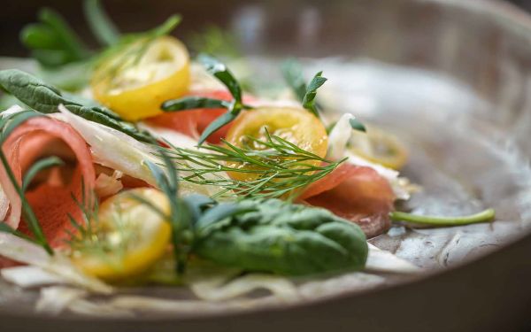 Plate of small green and yellow stacked canapes, on cover of 'Wild Cooking, Surprising Seasonal Dishes With Fresh Vegetables and Fruits', by Lannoo Publishers.