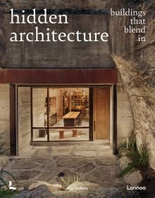 Illuminated interior living space, surrounded by carved rock, on cover of 'Hidden Architecture, Buildings that Blend In', by Lannoo Publishers