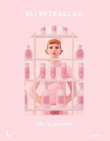 Book cover of Eli Rezkallah, Life in Plastik, with a model in pink tunic and hat, standing behind shelves of pink plastic product bottles. Published by Lannoo Publishers.
