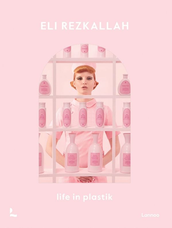 Book cover of Eli Rezkallah, Life in Plastik, with a model in pink tunic and hat, standing behind shelves of pink plastic product bottles. Published by Lannoo Publishers.