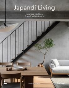 Calm, interior living space with pale wood table and chairs, low light fixture, white sofa, on cover of 'Japandi Living, Japanese Tradition. Scandinavian Design', by Lannoo Publishers.