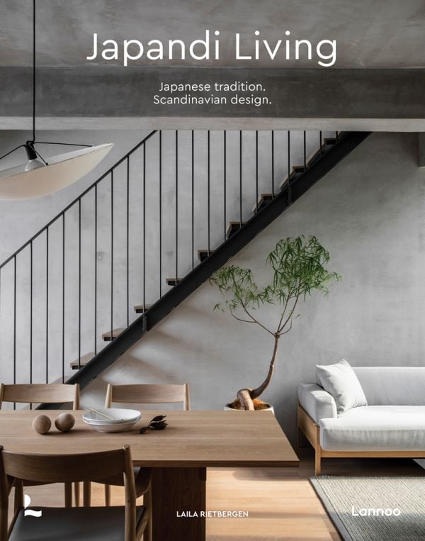 Book cover of Japandi Living, Japanese Tradition. Scandinavian Design, with a calm, interior living space with pale wood table and chairs, low light fixture, and white sofa. Published by Lannoo Publishers.