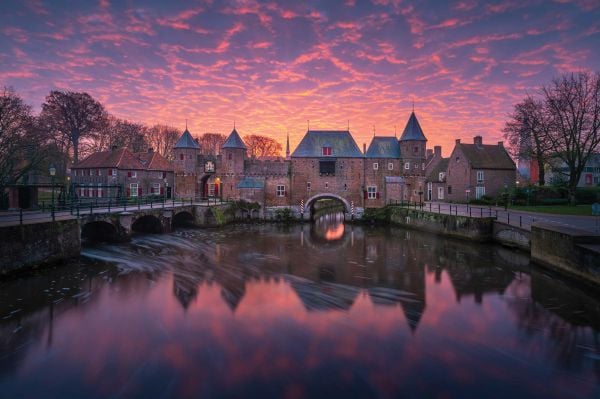 Book cover of The Beauty of the Netherlands: 10 Years of Photography by Albert Dros, with an aerial shot of an atmospheric landscape with windmills. Published by Lannoo Publishers.