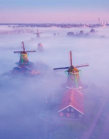 Book cover of The Beauty of the Netherlands: 10 Years of Photography by Albert Dros, with an aerial shot of an atmospheric landscape with windmills. Published by Lannoo Publishers.