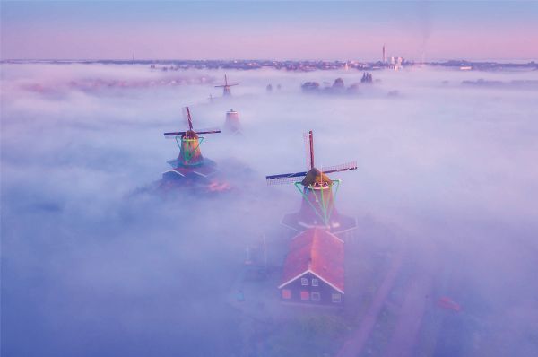 Book cover of The Beauty of the Netherlands: 10 Years of Photography by Albert Dros, with an aerial shot of an atmospheric landscape with windmills. Published by Lannoo Publishers.