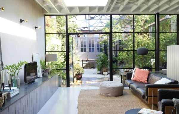 Book cover of London Interiors, featuring an interior living room with high ceiling, green walls, a blue velvet chair, and fireplace. Published by Lannoo Publishers.