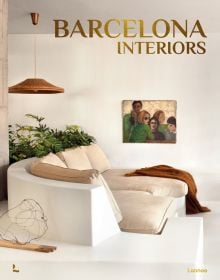 White Mediterranean interior space with white sofa, low hanging light, family portrait painting on wall, on cover of 'Barcelona Interiors', by Lannoo Publishers.