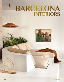 Book cover of Barcelona Interiors, with a white Mediterranean interior space with white sofa, low hanging light, and family portrait painting on wall. Published by Lannoo Publishers.