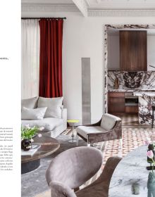 Book cover of Barcelona Interiors, with a white Mediterranean interior space with white sofa, low hanging light, and family portrait painting on wall. Published by Lannoo Publishers.