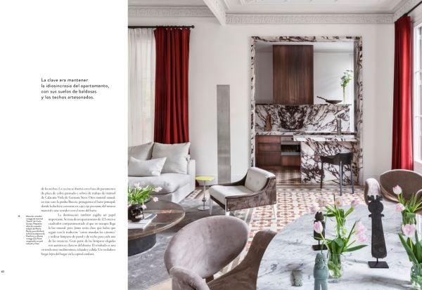 Book cover of Barcelona Interiors, with a white Mediterranean interior space with white sofa, low hanging light, and family portrait painting on wall. Published by Lannoo Publishers.