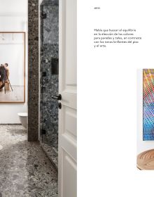 Book cover of Barcelona Interiors, with a white Mediterranean interior space with white sofa, low hanging light, and family portrait painting on wall. Published by Lannoo Publishers.