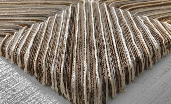 Book cover of Paperworld, featuring black cubes of recycled cardboard resembling small charcoal briquettes. Published by Lannoo Publishers.