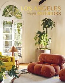 Interior living room with a bulbous terracotta armchair, large pot plant in corner, arched doors looking out into garden, on cover of 'Los Angeles Interiors', by Lannoo Publishers.