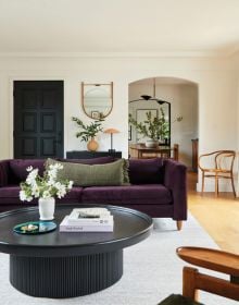 Interior living room with a bulbous terracotta armchair, large pot plant in corner, arched doors looking out into garden, on cover of 'Los Angeles Interiors', by Lannoo Publishers.