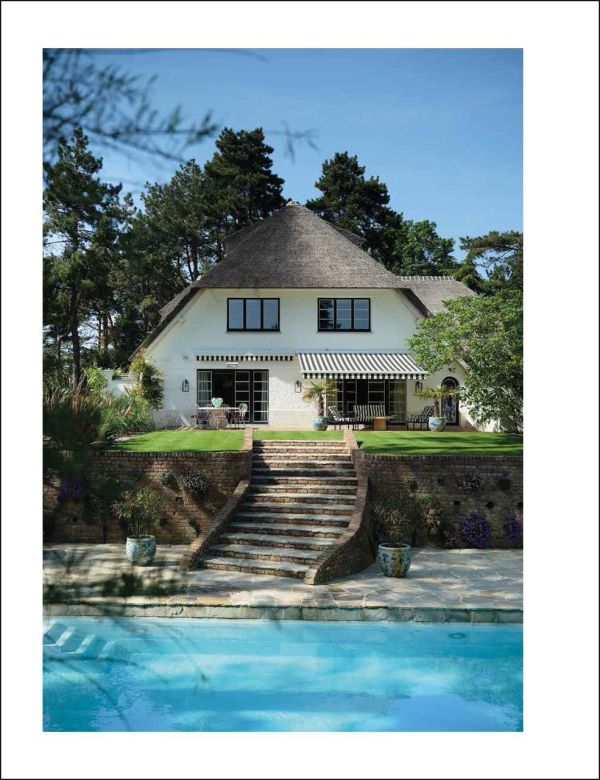 Book cover of Knokke Le Zoute Interiors, Living by the Sea, with white, open-plan kitchen/living room interior with wood floors. Published by Lannoo Publishers.