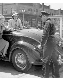 Petrol assistant in blue overalls filling up white car, woman leaning on side of bonnet, on cover of 'Gas Stations, An Illustrated History', by Lannoo Publishers.