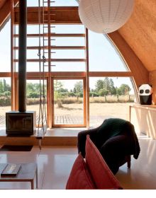 Warm terracotta interior living space with animal print seating, wood tables, fireplace, on cover of 'The Design of Retreat, Cabins, Cottages and Hideouts', by Lannoo Publishers.