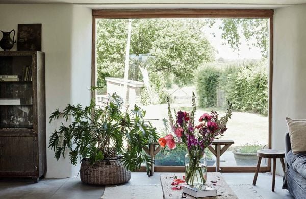 Book cover of Living in New Rustic Style, with an interior living room with exposed wood beams, pale walls and wood furniture. Published by Lannoo Publishers.