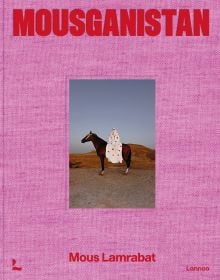 Pink linen book cover of Mous Lamrabat’s Mousganistan, with a figure in white robe sitting on horse surrounded by desert. Published by Lannoo Publishers.