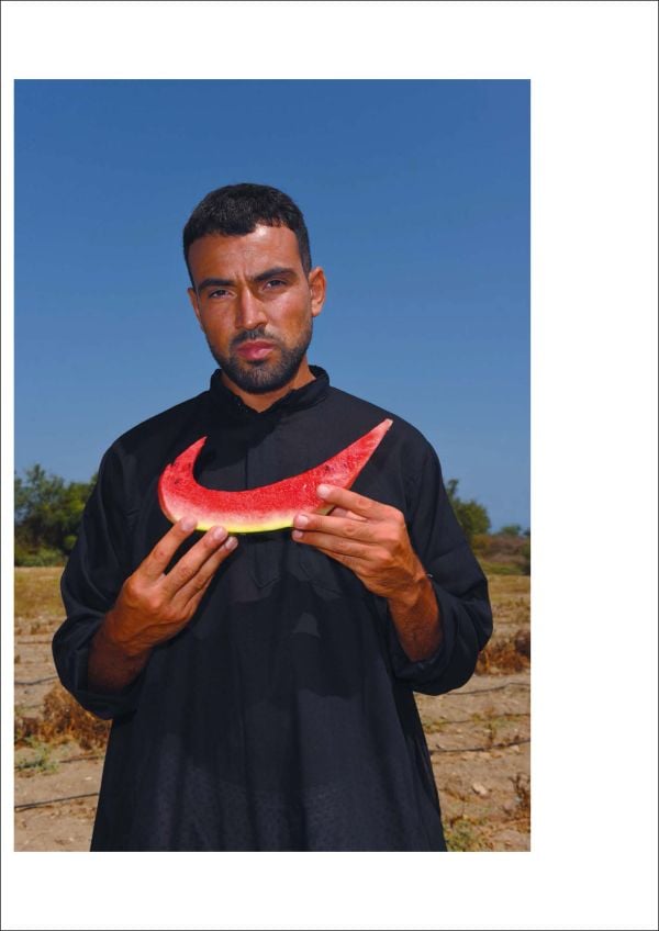 Pink linen book cover of Mous Lamrabat’s Mousganistan, with a figure in white robe sitting on horse surrounded by desert. Published by Lannoo Publishers.