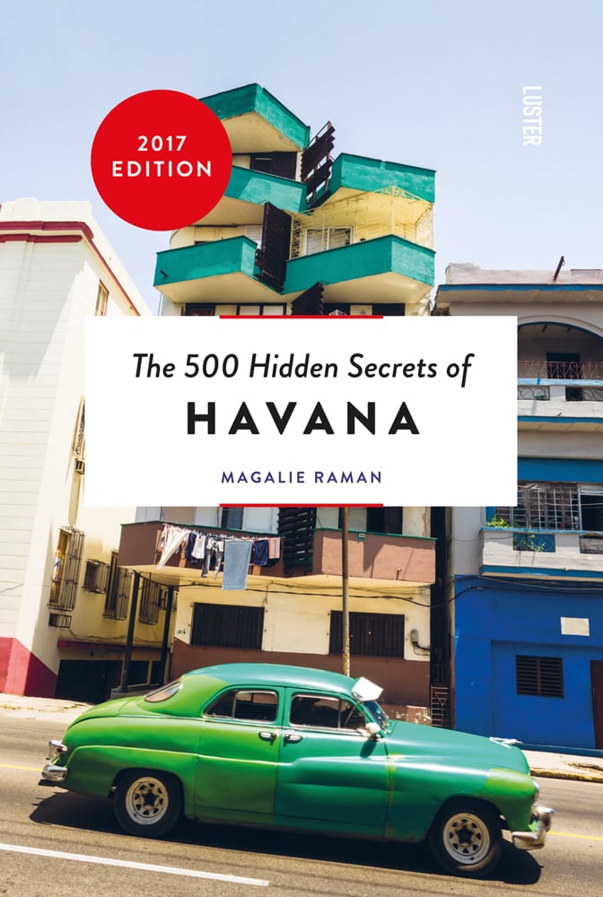 Green vintage car travelling on road past high-rise building, on cover of 'The 500 Hidden Secrets of Havana', by Luster Publishing.
