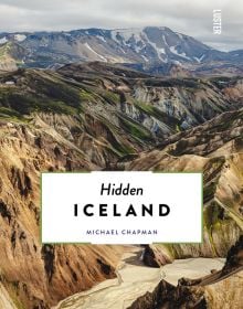 Aerial view of gold, blue and green mountainous landscape, on cover of 'Hidden Iceland', by Luster Publishing.