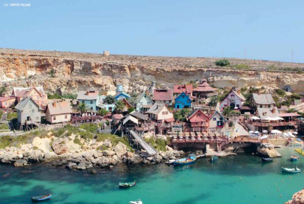 Book cover of Hidden Malta, with a row of multicoloured wooden seats, near harbour edge, with boat behind. Published by Luster Publishing.