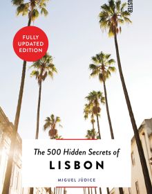 Book cover of The 500 Hidden Secrets of Lisbon, with a row of towering palm trees down sunny street. Published by Luster Publishing.