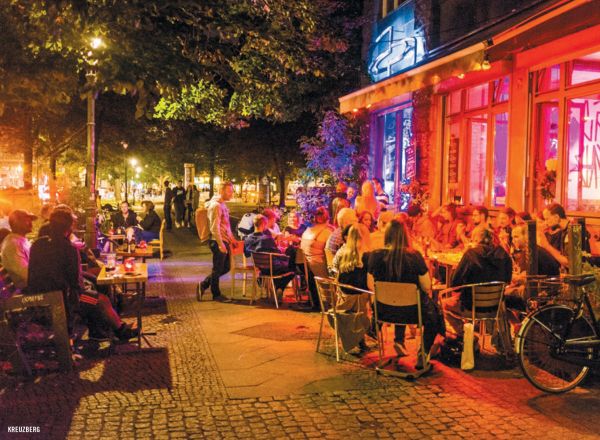Book cover of The 500 Hidden Secrets of Berlin, with Café Cinema bench with bunting and street art. Published by Luster Publishing.