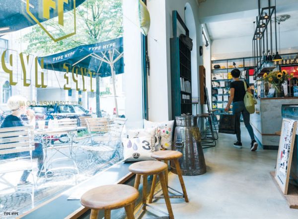 Book cover of The 500 Hidden Secrets of Berlin, with Café Cinema bench with bunting and street art. Published by Luster Publishing.