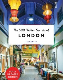 Brixton Village market in London, with hanging Chinese lanterns, The 500 Hidden Secrets of LONDON in black font, on white banner to centre.