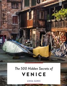 Book cover of The 500 Hidden Secrets of Venice, with a gondola workshop on canal edge. Published by Luster Publishing.