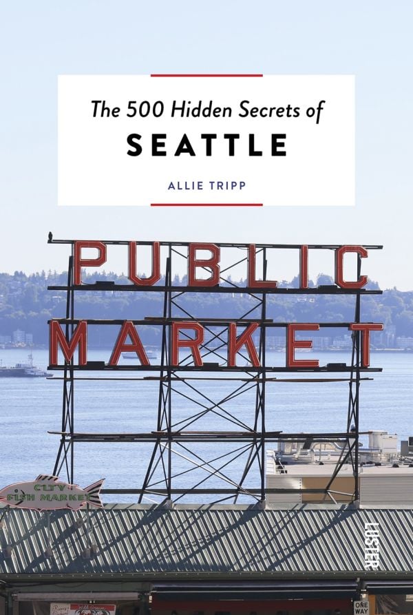 Book cover of The 500 Hidden Secrets of Seattle with the Pike Place market unlit neon sign above corrugated roof. Published by Luster Publishing.
