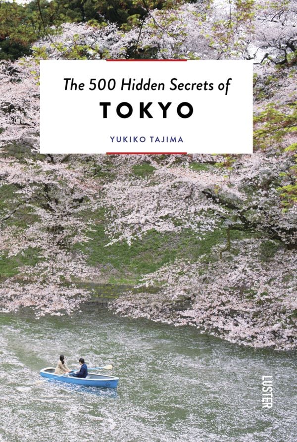 Book cover of The 500 Hidden Secrets of Tokyo, with a couple in boat on Imperial Palace moat, rowing beneath pink blossom trees. Published by Luster Publishing.