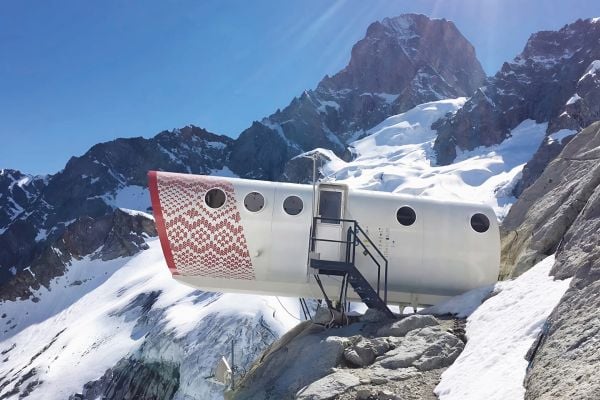 Book cover of Agata Toromanoff's Amazing Mountain Cabins: Architecture Worth the Hike, with a modern, hexagonal cabin resting on side of mountain. Published by Luster Publishing.