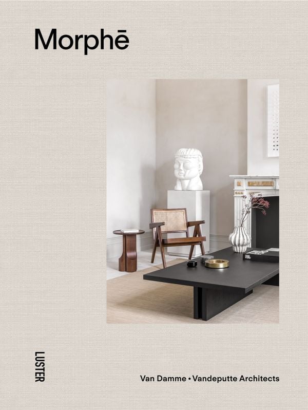 Linen book cover of Morph?, Van Damme - Vandeputte Architects, with an Interior space with low black coffee-table, white bust sculpture on plinth, wood chair, and white marble fireplace. Published by Luster Publishing.