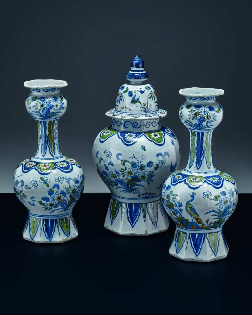 Collection of Dutch ceramic vessels, painted with flowers, on grey cover, Made in Holland in white font to centre