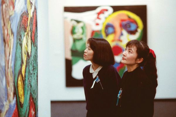 Book cover of APPEL: A life in photographs by Nico Koster, with the artist standing next to a large colorful sculpture. Published by Waanders Publishers.