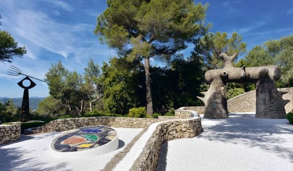 Book cover of Joan Miró: Sculptures, with the artist sitting on a chair in his studio. Published by Waanders Publishers.