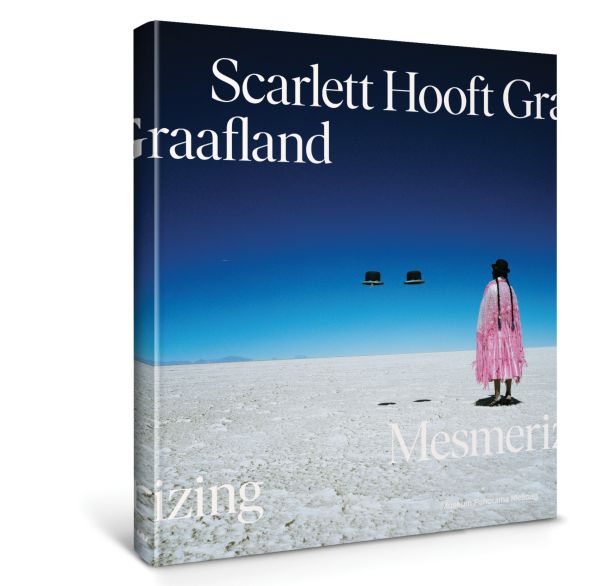 Book cover of Scarlett Hooft Graafland: Mesmerizing; featuring a figure standing in the desert, with two floating hats. Published by Waanders Publishers.