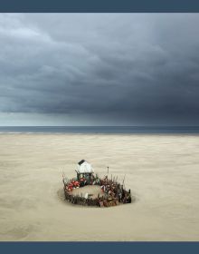 Sandy landscape with dark moody clouds above, small shack on silts, on landscape cover of 'Eiland', by Hannibal Books.