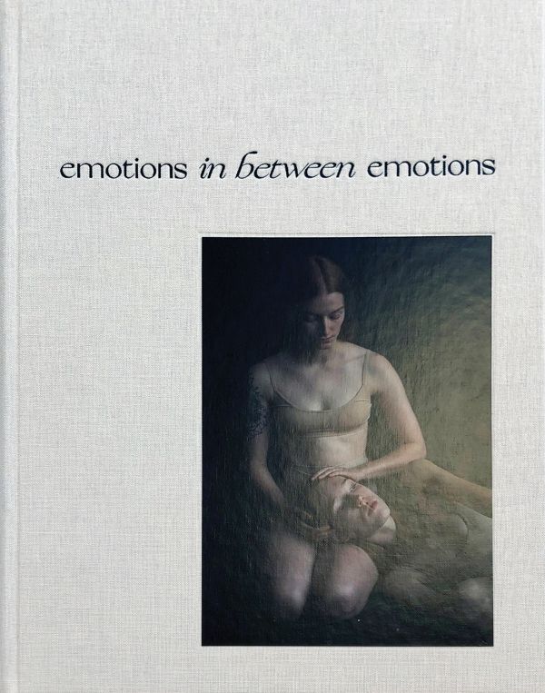 Book cover of Emotions In Between Emotions, with two female figures; one resting head on the others lap. Published by Hopper&Fuchs.